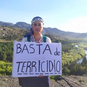 Moira Millán sosteniendo un cartel con el mensaje, basta de terricidio
